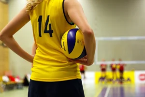 En ung spelare i gul tröja som dribblar med en fotboll i en typisk svensk inomhushall för idrott.