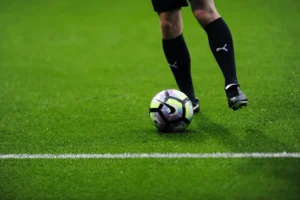 Finansiering konstgräsplan - fotbollsspelare och boll på modern konstgräsplan utan mikroplaster