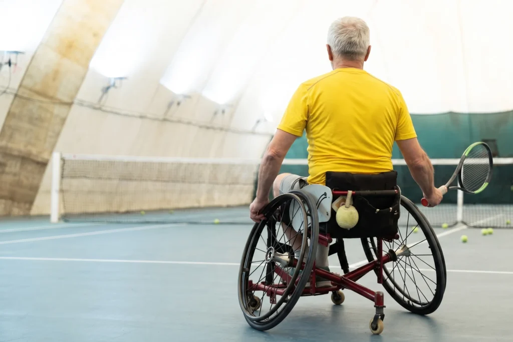 Äldre man i rullstol spelar tennis i en tillgänglig idrottsanläggning byggd med miljonstöd från Allmänna Arvsfonden.